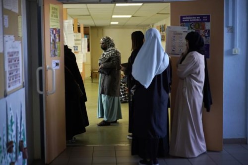FILE - Women wait in line before voting for the first round of the presidential election at a polling station Sunday, April 10, 2022 in the Malpasse northern district of Marseille, southern France. French voters head to polls on Sunday in a runoff vote between centrist incumbent Emmanuel Macron and nationalist rival Marine Le Pen, wrapping up a campaign that experts have seen as unusually dominated by discriminatory discourse and proposals targeting immigration and Islam. (AP Photo/Daniel Cole, File)