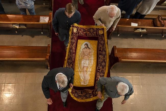 Members of the congregation preform the procession of the Holy Shroud on Good Friday at Transfiguration Of Our Lord Ukrainian Catholic Church, in Shamokin, Pa., Friday, April 15, 2022. The Holy Shroud is taken outside around the church to symbolize the funeral procession of Christ to the grave. The Holy Shroud is a cloth depicting the Savior lying in the tomb. (AP Photo/Carolyn Kaster)