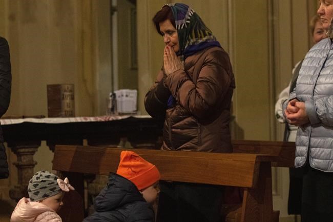 A Ukrainian woman prays during an orthodox Easter service for Ukrainians, both residents and refugees, in Melzo, in the outskirts of Milan, Saturday night, April 23, 2022. (AP Photo/Alberto Pellaschiar)
