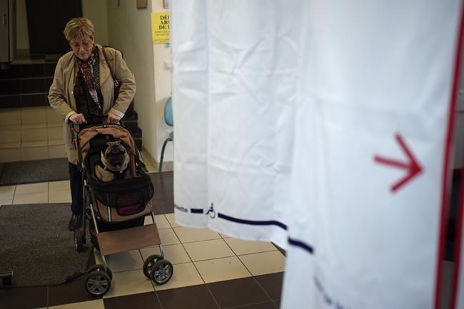A woman pushes a dog in a buggy as she arrives to cast her vote in the second round of the French presidential election in Marseille, southern France Sunday, April 24, 2022. Far-right candidate Marine Le Pen and centrist candidate and French President Emmanuel Macron are facing each other in a rematch of the 2017 presidential election runoff. (AP Photo/Daniel Cole)