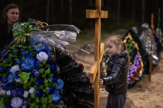 Darya Piven, 33, looks as her daughter Zlata, 6, as she visits the graves of her parents Nadiya Myakushko, 69, and Volodymyr Cherednichenko, 75, who were killed by Russian army in Irpin on March 24, in Irpin, on the outskirts of Kyiv, Monday, April 25, 2022. (AP Photo/Emilio Morenatti)