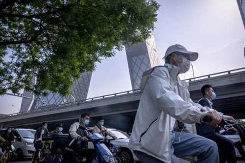Commuters wearing face masks wait at an intersection in the central business district in Beijing, Thursday, May 5, 2022. Hong Kong on Thursday reopened beaches and pools in a relaxation of COVID-19 restrictions, while China's capital Beijing began easing quarantine rules for arrivals from overseas. (AP Photo/Mark Schiefelbein)