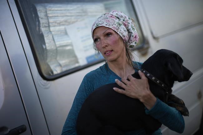 Iuliia holds her dog, Chackie, upon her arrival to a reception center for displaced people in Zaporizhzhia, Ukraine, Sunday, May 8, 2022. Iuliia drove her grandmother's friend from Kherson as thousands of Ukrainian continue to leave Russian occupied areas. (AP Photo/Francisco Seco)