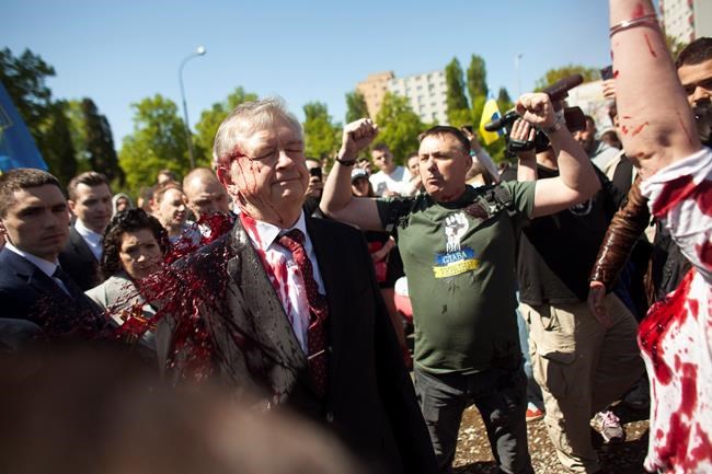 Activists hold up their arms as Russian Ambassador to Poland, Ambassador Sergey Andreev is covered with red paint in Warsaw, Poland, Monday, May 9, 2022. Protesters have thrown red paint on the Russian ambassador as he arrived at a cemetery in Warsaw to pay respects to Red Army soldiers who died during World War II. Ambassador Sergey Andreev arrived at the Soviet soldiers cemetery on Monday to lay flowers where a group of activists opposed to Russia’s war in Ukraine were waiting for him. (AP Photo/Maciek Luczniewski)
