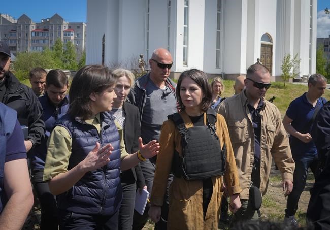 German Foreign Minister Annalena Baerbock, center, and Ukrainian Prosecutor General Iryna Venediktova talk as they stand near a mass grave in Bucha, on the outskirts of Kyiv, Ukraine, Tuesday, May 10, 2022. (AP Photo/Efrem Lukatsky)