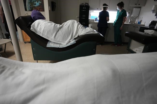 FILE - A woman naps, bundled up against the air conditioning, as she waits to have an abortion, Saturday, Oct. 9, 2021, at Hope Medical Group for Women in Shreveport, La. A bill scheduled for debate Thursday, May 12, 2022, in the Louisiana House would make women who get abortions subject to criminal prosecution and prison — a position that has drawn opposition from Louisiana’s anti-abortion governor and groups including Louisiana Right to Life and the Louisiana Conference of Catholic Bishops. (AP Photo/Rebecca Blackwell, File)