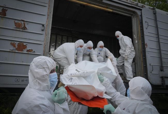 Ukrainian servicemen load bodies of Russian soldiers into a railway refrigerator carriage in Kyiv, Ukraine, Friday, May 13, 2022. (AP Photo/Efrem Lukatsky)