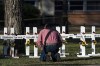 Pastor Daniel Myers kneels in front of crosses bearing the names of Tuesday's shooting victims while praying for them at Robb Elementary School in Uvalde, Texas, Thursday, May 26, 2022. (AP Photo/Jae C. Hong)
