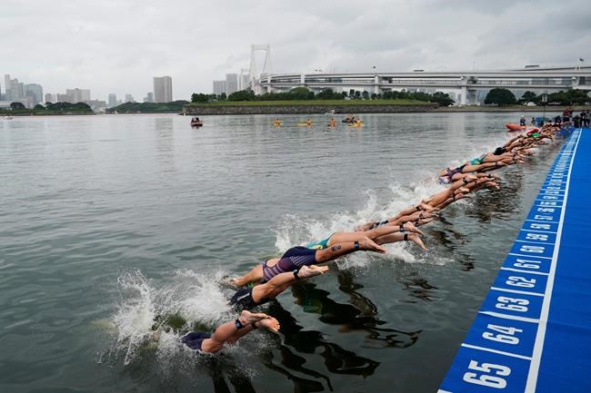 FILE - In this Aug. 15, 2019, file photo, athletes dive into the water at the start line during a women's triathlon test event at Odaiba Marine Park, a venue for marathon swimming and triathlon at the Tokyo 2020 Olympics, in Tokyo. The IOC moved next year’s Tokyo Olympic marathons and race walks out of the Japanese capital to avoid the stifling heat and humidity. Some swimmers and an 11,000-member coaching body want similar treatment: find an alternative to the distance-swimming venue in Tokyo Bay known as the “Odaiba Marine Park.”(AP Photo/Jae C. Hong, File)