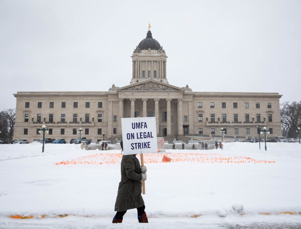 A striker marches outside the legislature. (Jessica Lee / Winnipeg Free Press files)
