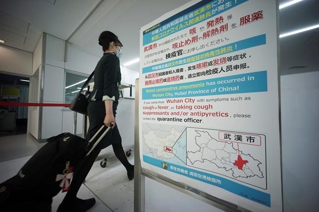 A flight attendant walks through body temperature scanners and a notice board on coronavirus at Narita international airport in Narita, near Tokyo, Thursday, Jan. 23, 2020. China closed off the city of more than 11 million people Thursday in an unprecedented effort to try to contain a deadly new viral illness that has sickened hundreds and spread to other cities and countries in the Lunar New Year travel rush. (AP Photo/Eugene Hoshiko)