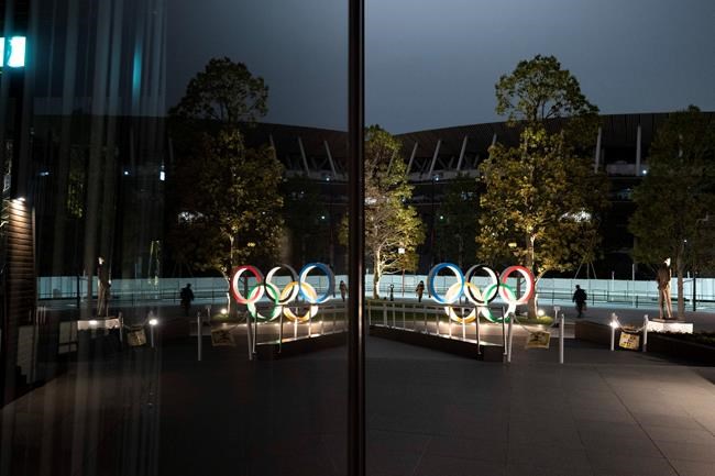 The Olympic rings are reflected on the facade of Japan Olympic Museum Monday, March 30, 2020, in Tokyo. The Tokyo Olympics will open next year in the same time slot scheduled for this year's games. Tokyo organizers said Monday the opening ceremony will take place on July 23, 2021. (AP Photo/Jae C. Hong)