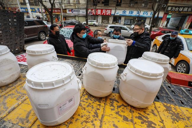 Workers unload canisters of disinfectant from a truck in Wuhan in central China's Hubei Province, Tuesday, Jan. 28, 2020. Hong Kong's leader announced Tuesday that all rail links to mainland China will be cut starting Friday as fears grow about the spread of a new virus. (Chinatopix via AP)
