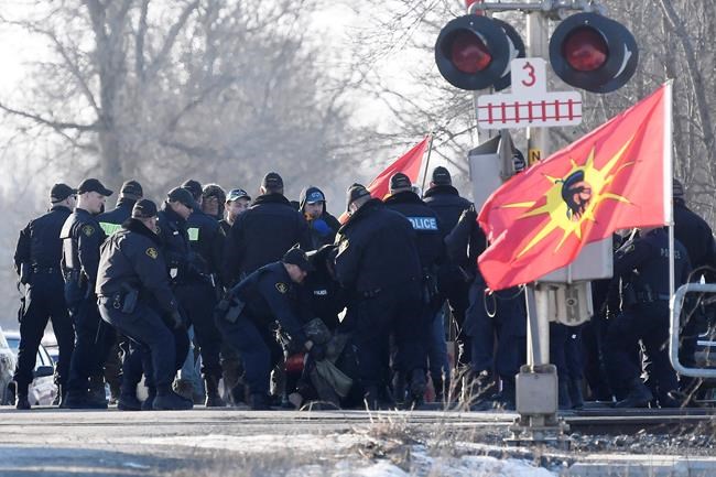 Ontario Provincial Police officers arrest a protester at a rail blockade in Tyendinaga Mohawk Territory, near Belleville, Ont., on Monday Feb. 24, 2020, as they protest in solidarity with Wet'suwet'en Nation hereditary chiefs attempting to halt construction of a natural gas pipeline on their traditional territories. THE CANADIAN PRESS/Adrian Wyld