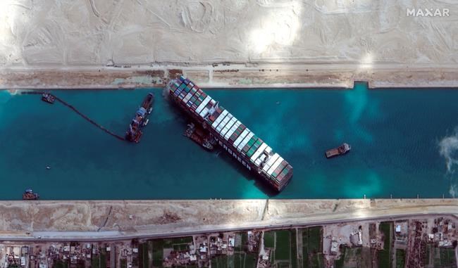 This satellite image from Maxar Technologies shows the cargo ship MV Ever Given stuck in the Suez Canal near Suez, Egypt, Sunday, March 28, 2021. Two additional tugboats sped Sunday to Egypt's Suez Canal to aid efforts to free a skyscraper-sized container ship wedged for days across the crucial waterway, even as major shippers increasingly divert their boats out of fear the vessel may take even longer to free. (©Maxar Technologies via AP)