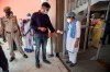 An Indian health worker checks temperature of a person arriving for the oath taking ceremony of Assam's new chief minister Himanta Biswa Sarma in Gauhati, Assam, India, Monday, May 10, 2021. (AP Photo/Anupam Nath)