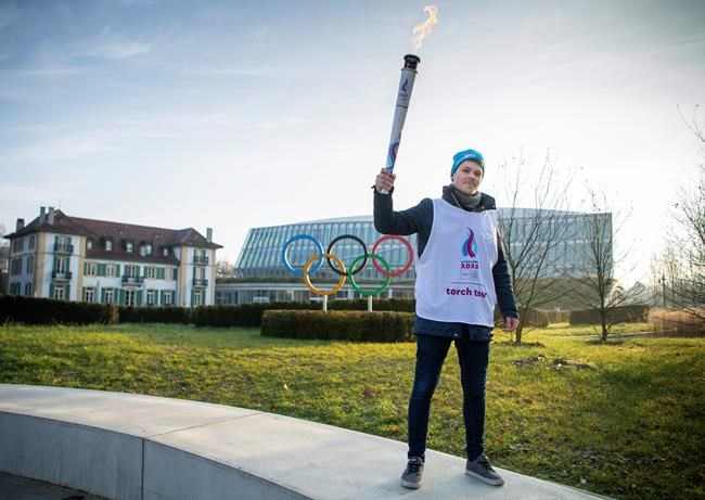 Nathanael Pianta poses with the Lausanne 2020 Youth Olympic Flame alongside the Olympic Rings outside Olympic House during the the final Torch Relay. The Winter Youth Olympic Games, Lausanne, Switzerland, Wednesday, Jan. 8, 2020. (Joel Marklund/Olympic Information Service via AP)