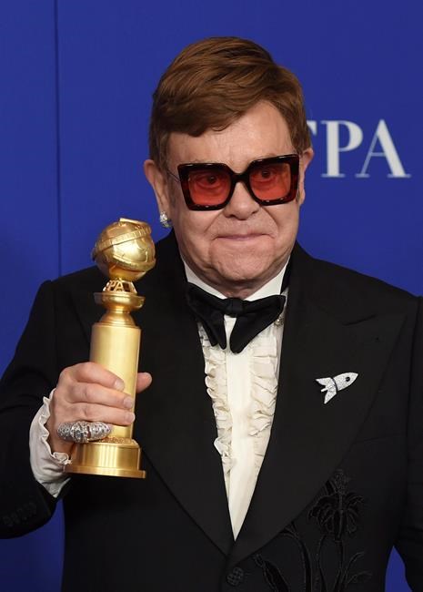 Elton John poses in the press room with the award for best original score in a motion picture for