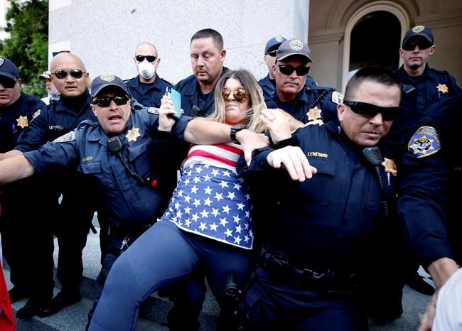 A protester is detained by California Highway Patrol officers during a demonstration against Gov. Gavin Newsom's stay-at-home orders due to the coronavirus pandemic, at the Capitol in Sacramento, Calif., Friday, May 1, 2020. Several people were taken into custody during the protest calling for Newsom to ease the restrictions and allow people return to work. (AP Photo/Rich Pedroncelli)