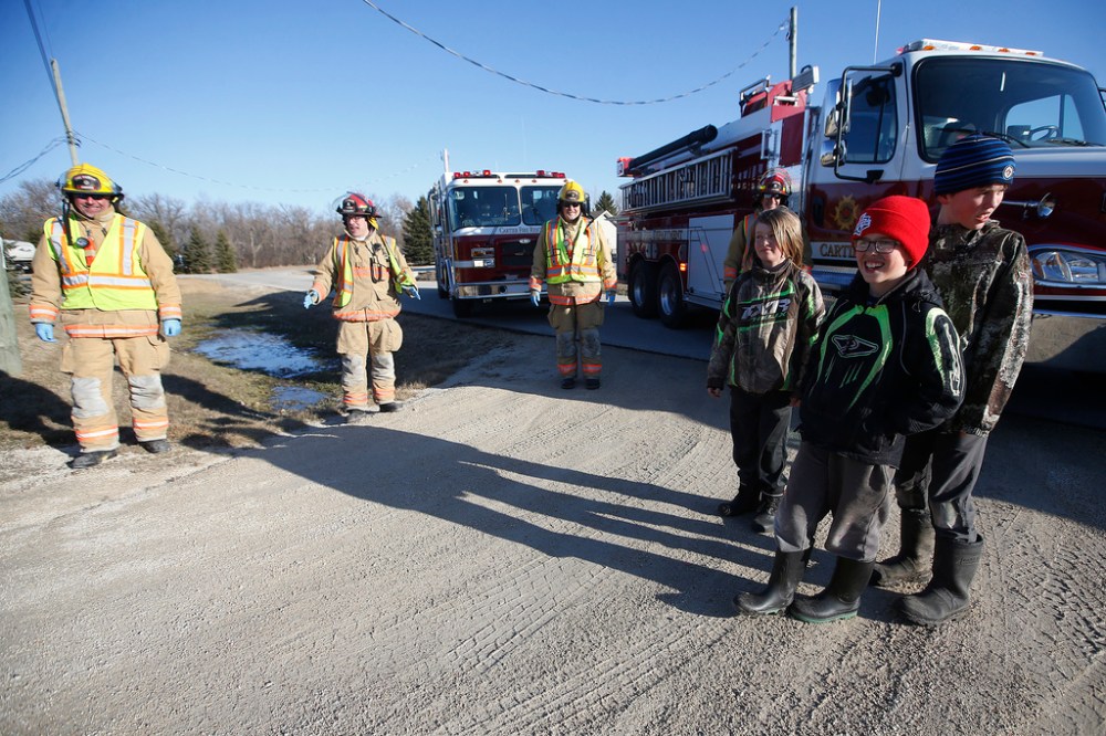 JOHN WOODS / WINNIPEG FREE PRESS
Firefighters from the Cartier Fire Department, from left, Elie James Krahn, Luc Mallet, Bob Bilous, and Murray Emond, sing Jonas Dufresne, centre, “Happy Birthday” as his brothers Luke and Rylan look on outside their house Wednesday.