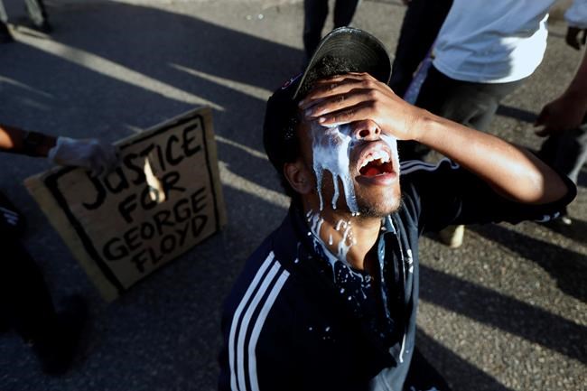 A protester is doused with milk Friday, May 29, 2020, in Minneapolis. Protests continued following the death of George Floyd, who died after being restrained by Minneapolis police officers on Memorial Day. (AP Photo/John Minchillo)