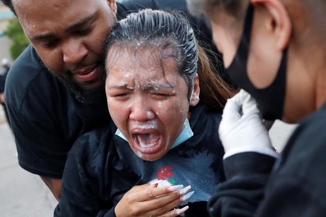 A woman is helped after being hit with pepper spray after curfew on Sunday, May 31, 2020 in Minneapolis. Protests continued following the death of George Floyd, who died after being restrained by Minneapolis police officers on Memorial Day. (AP Photo/John Minchillo)
