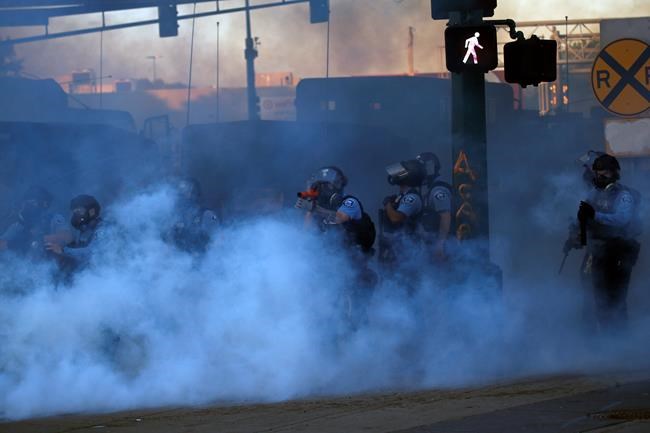 A police officer prepares to shoot tear gas Friday, May 29, 2020, in Minneapolis. Protests continued following the death of George Floyd who died after being restrained by Minneapolis police officers on Memorial Day. (AP Photo/John Minchillo)