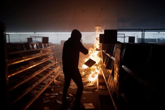 People loot then burn an Office Depot Friday, May 29, 2020, in Minneapolis. Protests continued following the death of George Floyd, who died after being restrained by Minneapolis police officers on Memorial Day. (AP Photo/John Minchillo)