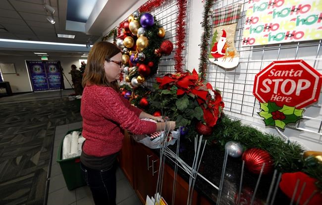 Volunteer Nicole Schreiner places a display of poinsettias in the NORAD Tracks Santa center at Peterson Air Force Base, Monday, Dec. 23, 2019, in Colorado Springs, Colo. More than 1,500 volunteers will answer an estimated 140,000 telephone inquiries to learn of the whereabouts of Santa Claus on Christmas Eve. (AP Photo/David Zalubowski)