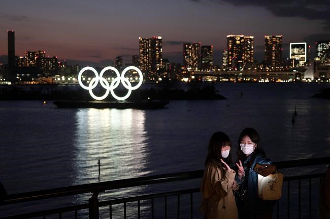 Two women take a selfie with the Olympic rings in the background in the Odaiba section of Tokyo, Thursday, March 12, 2020. THE CANADIAN PRESS/Jae C. Hong