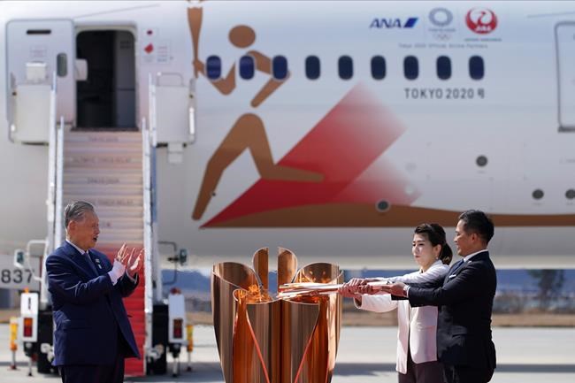 Three-time Olympic gold medalists Tadahiro Nomura, right, and Saori Yoshida light the torch as Tokyo 2020 Olympics chief Yoshiro Mori, left, watches during Olympic Flame Arrival Ceremony at Japan Air Self-Defense Force Matsushima Base in Higashimatsushima in Miyagi Prefecture, north of Tokyo, Friday, March 20, 2020. THE CANADIAN PRESS/AP-Eugene Hoshiko