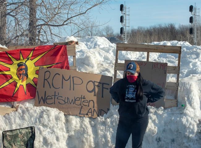 A member of the Mohawk community stands near the blockade of the commuter rail line Wednesday, February 12, 2020 in Kahnawake, Quebec. THE CANADIAN PRESS/Ryan Remiorz