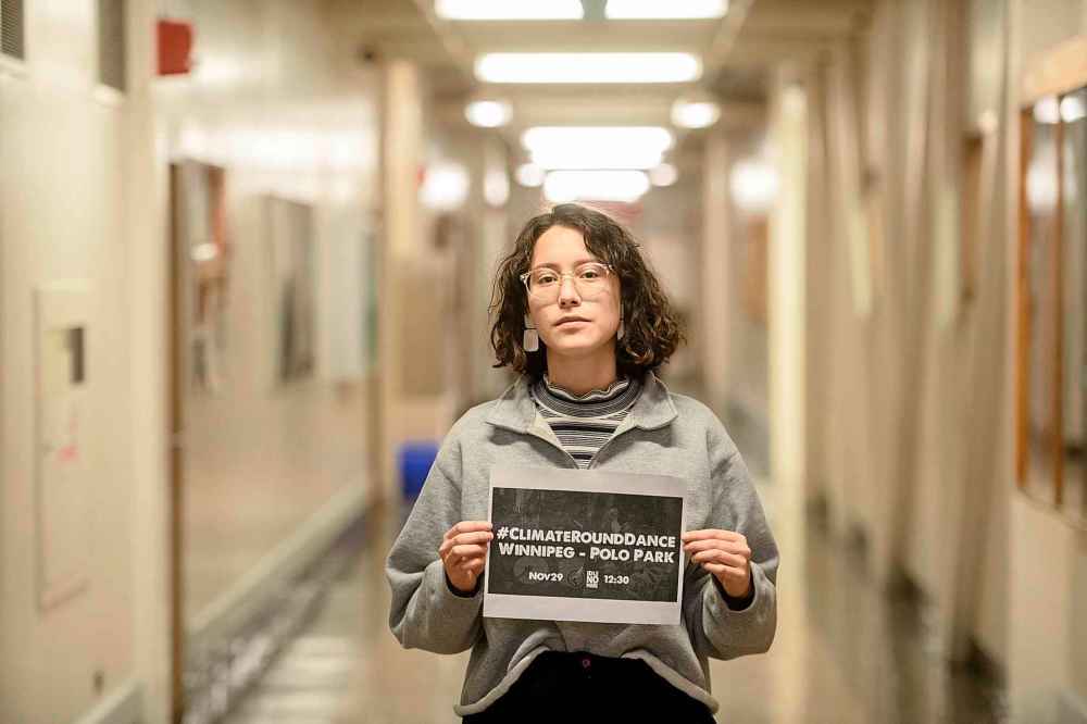 Dominique Carrière holds up a sign inside the U of W for the up coming Climate Round Dance being held at Polo Park Mall Friday afternoon. (Mike Sudoma / Winnipeg Free Press)