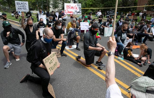 People including Kevin Antlitz, an Anglican priest, left, take a knee during a protest of the visit of President Donald Trump to the Saint John Paul II National Shrine, Tuesday, June 2, 2020, in Washington. Many demonstrators present said they were dismayed when Trump staged a visit to the historic St. John's Church across from the White House and held up a Bible after authorities had cleared the area of peaceful protesters. Protests continue over the death of George Floyd, who died after being restrained by Minneapolis police officers. (AP Photo/Jacquelyn Martin)
