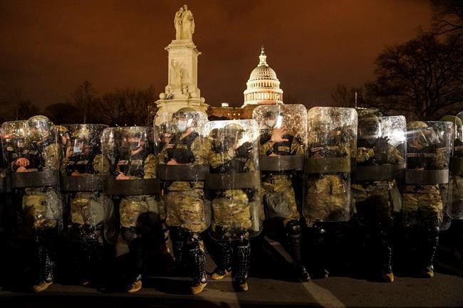 DC National Guard stand outside the Capitol, Wednesday night, Jan. 6, 2021, after a day of rioting protesters. It's been a stunning day as a number of lawmakers and then the mob of protesters tried to overturn America's presidential election, undercut the nation's democracy and keep Democrat Joe Biden from replacing Trump in the White House. (AP Photo/John Minchillo)
