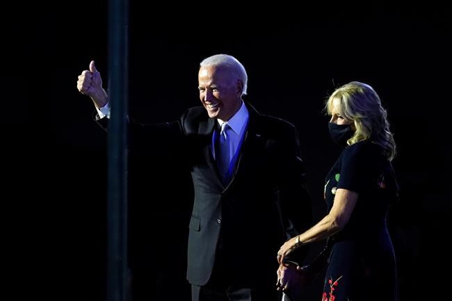 President-elect Joe Biden stands on stage with his wife Jill Biden as he gives the thumbs-up to the cheering crowd beyond the protective glass, Saturday, Nov. 7, 2020, in Wilmington, Del. (AP Photo/Carolyn Kaster)