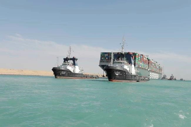 In this photo released by Suez Canal Authority, the Ever Given, a Panama-flagged cargo ship is accompanied by Suez Canal tugboats as it moves in the Suez Canal, Egypt, Monday, March 29, 2021. Salvage teams on Monday set free a colossal container ship that has halted global trade through the Suez Canal, bringing an end to a crisis that for nearly a week had clogged one of the world's most vital maritime arteries. (Suez Canal Authority via AP)
