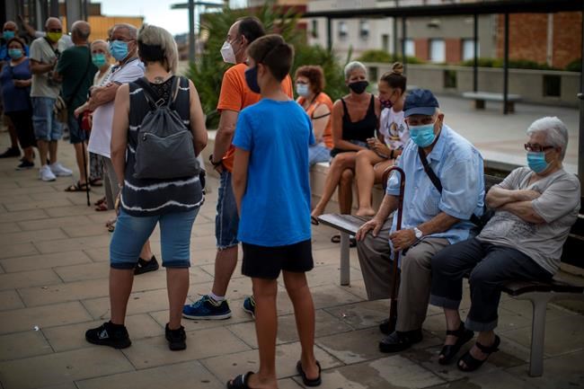 People wearing face masks wait their turn to be called for a PCR test for the COVID-19 outside a local clinic in Santa Coloma de Gramanet in Barcelona, Spain, Tuesday, Aug. 11, 2020. (AP Photo/Emilio Morenatti)
