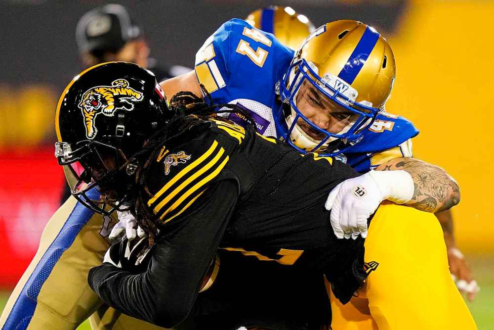 CP
Winnipeg Blue Bombers linebacker Tanner Cadwallader (47) tackles Hamilton Tiger-Cats defensive back Tunde Adeleke (2) during the first half. (Frank Gunn / The Canadian Press)