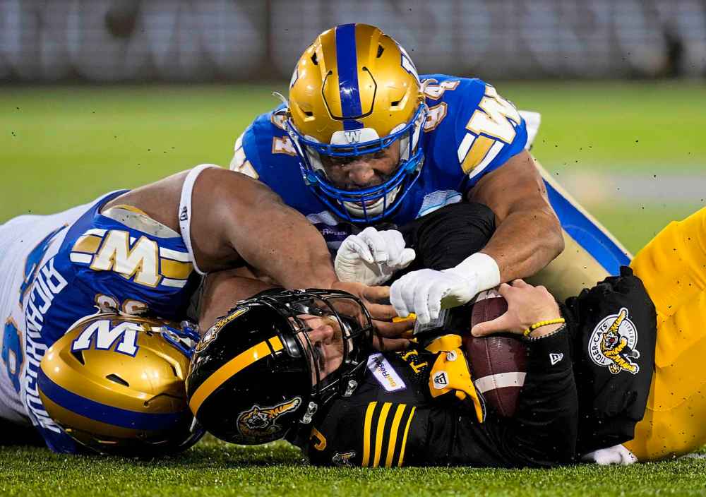 CP
Hamilton Tiger-Cats quarterback Dane Evans (9) is sacked by Winnipeg Blue Bombers defensive end Jackson Jeffcoat (94) and defensive lineman Steven Richardson (98) during the first half. (Nathan Denette / The Canadian Press)