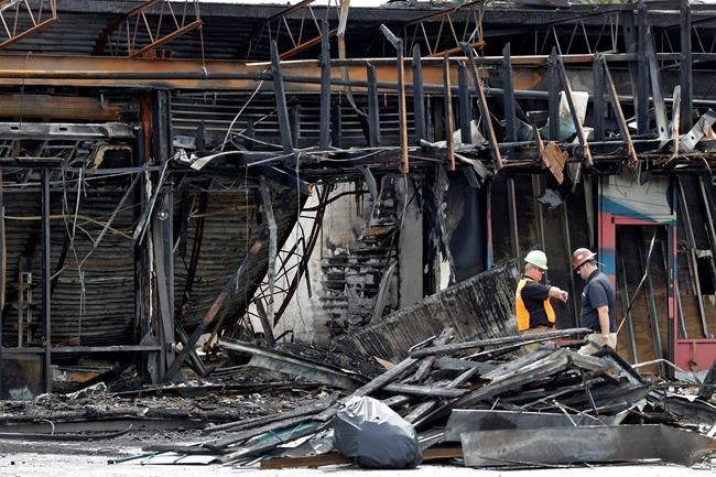 Two workers inspect the damage to a sporting goods store, Monday, June 1, 2020, in Tampa, Fla., after the establishment was looted and burned by protesters during a demonstration Saturday night. Several counties across Florida issued curfews to curb large crowds gathering to protest the killings of black people by police. (AP Photo/Chris O'Meara)