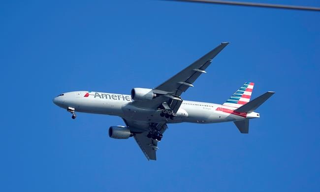 An American Airlines Boeing 777 is framed by utility wires as it prepares to land at Miami International Airport, Wednesday, Jan. 27, 2021, in Miami. The airline said Thursday that it lost $2.2 billion in the fourth quarter, with revenue plunging by nearly two-thirds from a year earlier. And the airline lost $8.9 billion for the full year after earning nearly $1.7 billion in 2019. .(AP Photo/Wilfredo Lee)