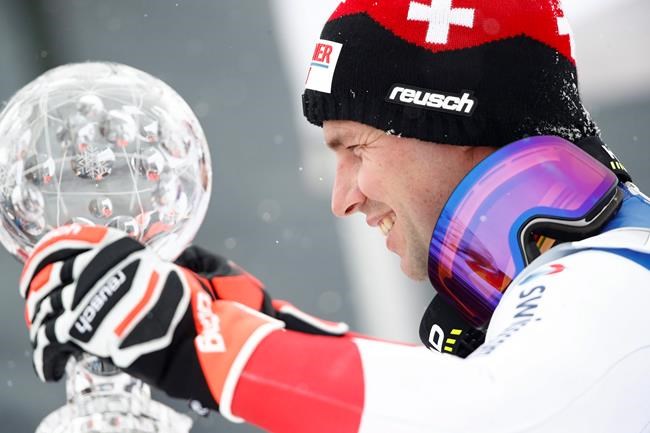 Switzerland's Beat Feuz holds the trophy of the alpine ski, men's World Cup downhill, in Lenzerheide, Switzerland, Wednesday, March 17, 2021. (AP Photo/Gabriele Facciotti)