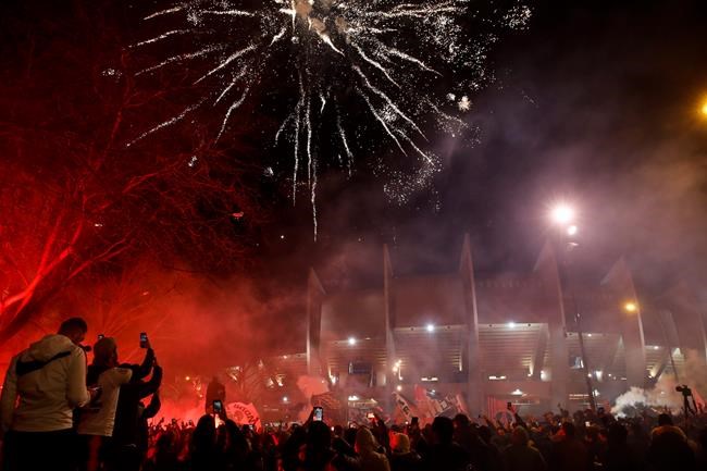 PSG supporters gather outside the Parc des Princes stadium during a Champions League round of 16 second leg soccer match between Paris-Saint-Germain and Borussia Dortmund in Paris Wednesday, March 11, 2020. The match is played behind closed doors without spectators due to the COVID-19 outbreak. For most people, the new coronavirus causes only mild or moderate symptoms, such as fever and cough. For some, especially older adults and people with existing health problems, it can cause more severe illness, including pneumonia. (AP Photo/Christophe Ena)