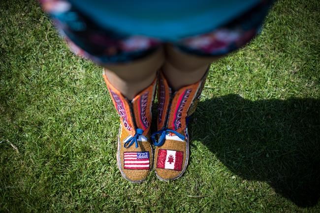 Red Moon Roberts, 16, from the Sto:lo Nation near Chilliwack, B.C., wears moccasins bearing the flags of the United States and Canada crafted from beads as she poses for a photograph before competing during the final day of the 32nd annual Squamish Nation Youth Powwow, in West Vancouver, B.C., on Sunday July 14, 2019. THE CANADIAN PRESS/Darryl Dyck