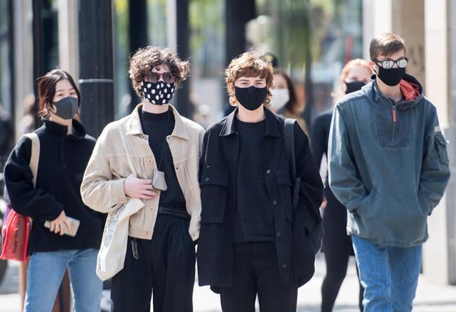 People wear face masks as they wait to cross a street in Montreal, Monday, September 21, 2020, as the COVID-19 pandemic continues in Canada and around the world. THE CANADIAN PRESS/Graham Hughes