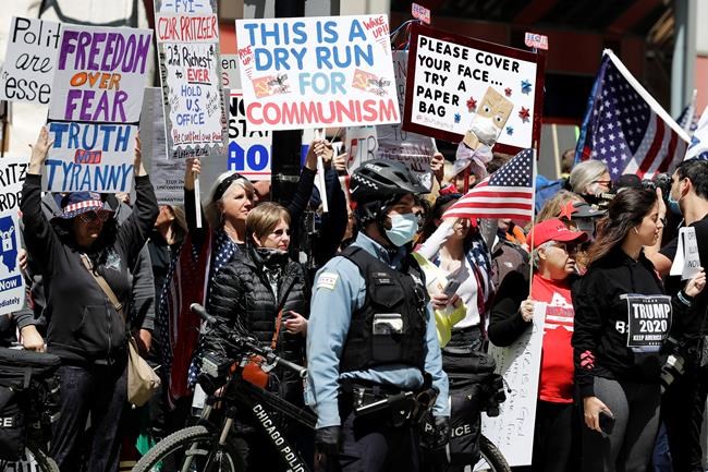 Protesters rally against Illinois stay-at-home order outside the Thompson Center in downtown Chicago, Friday, May 1, 2020. The Friday demonstration is the latest in a series of protests around the country against stay-at-home orders designed to slow the spread of the coronavirus. (AP Photo/Nam Y. Huh)