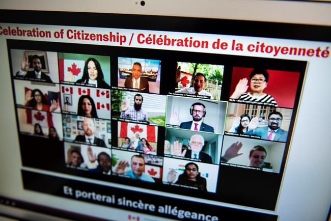 Minister of Immigration, Refugees and Citizenship Marco Mendicino, second from top right, leads participants as they raise their hands to swear the oath to become Canadian citizens during a virtual citizenship ceremony held over livestream due to the COVID-19 pandemic, on Canada Day, Wednesday, July 1, 2020, seen on a computer in Ottawa. THE CANADIAN PRESS/Justin Tang