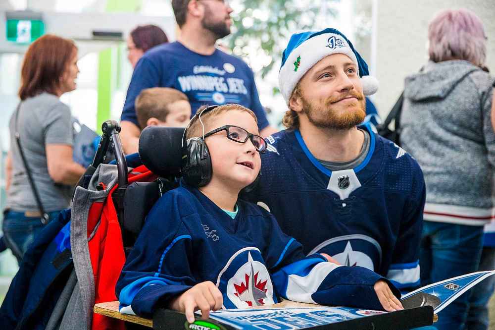 MIKAELA MACKENZIE / WINNIPEG FREE PRESS
Jacoby Zebinski, seven, poses for a photo with goalie Laurent Brossoit at the Winnipeg Jets' annual holiday visit to the Children's Rehab Centre in Winnipeg on Monday.