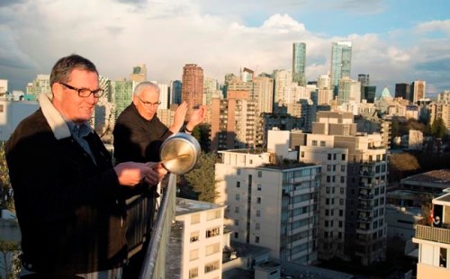 Reverend Gary Paterson, right, and his partner Tim Stevenson clap and beat on a pot with a wooden spoon as part of a tribute to health care workers in Vancouver, B.C. Tuesday, March 24, 2020. Thousands of people in Vancouver's west end have been going out on their balconies to applaud the front line heath care workers each night at 7pm. THE CANADIAN PRESS/Jonathan Hayward